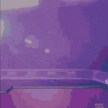 a person is standing in front of a purple background that says mbc on it .