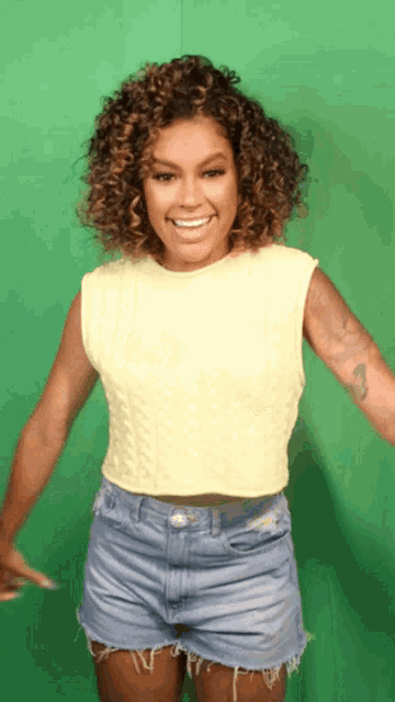 a woman with curly hair is wearing shorts and a yellow sweater