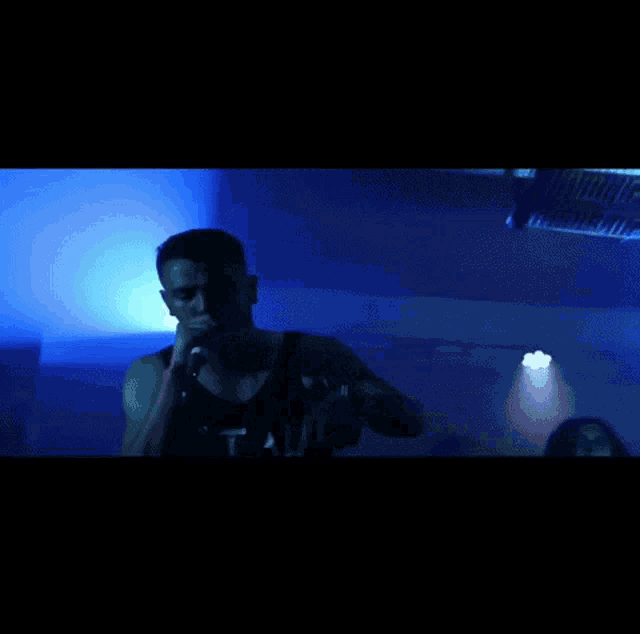 a man singing into a microphone wearing a tank top that says vital