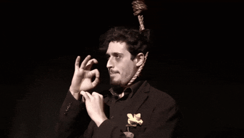 a man in a black suit has a rope hanging from his neck