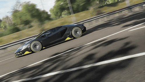 a black and yellow sports car is driving on a highway