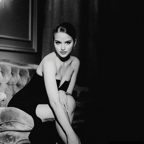 a woman in a strapless black dress sits on a couch
