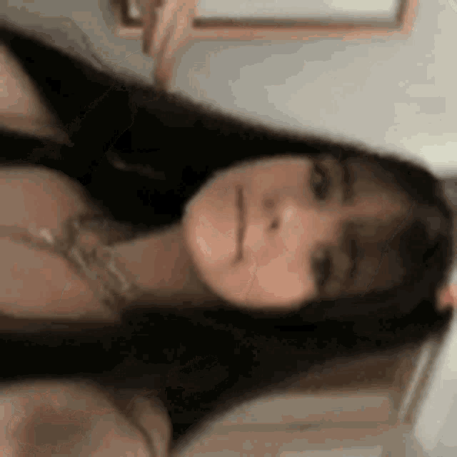 a woman is taking a selfie in front of a mirror while wearing a necklace .
