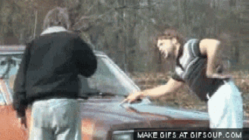 a man is standing next to a woman who is cleaning a car .