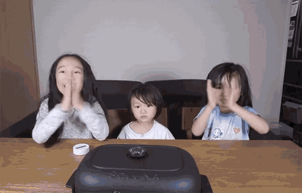 three little girls are sitting at a table with their hands on their faces in front of a sesame brand pan