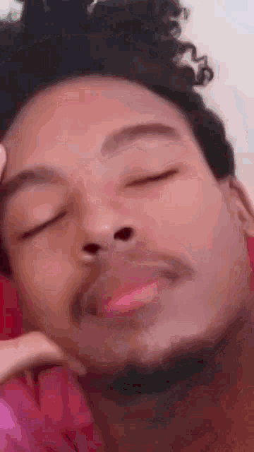 a close up of a man with his eyes closed and his hand on his face .