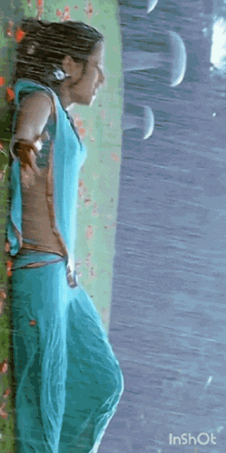 a woman is standing in the rain wearing a blue saree .
