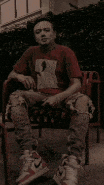 a man in a red shirt is sitting on a red bench with lightning coming out of his shoes