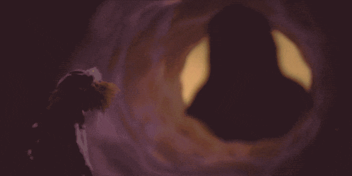 a silhouette of a person in a tunnel with a yellow light behind them