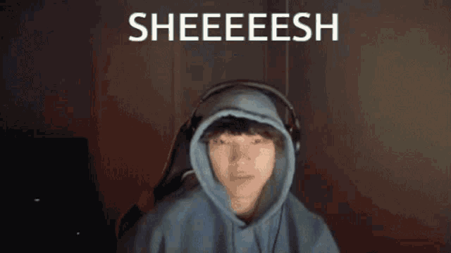 a person wearing headphones and a hoodie with the words sheeeesh written on the bottom .