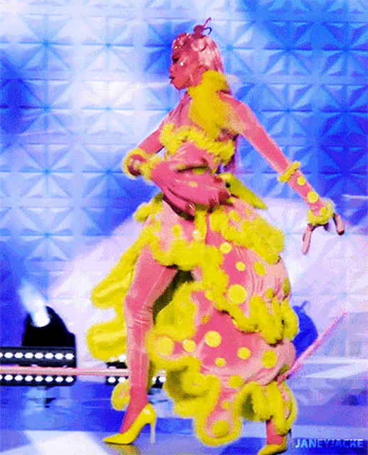 a woman in a pink and yellow dress is dancing on stage