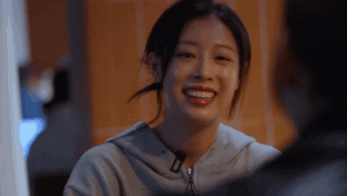 a woman wearing a grey nike hoodie smiles while looking at a man
