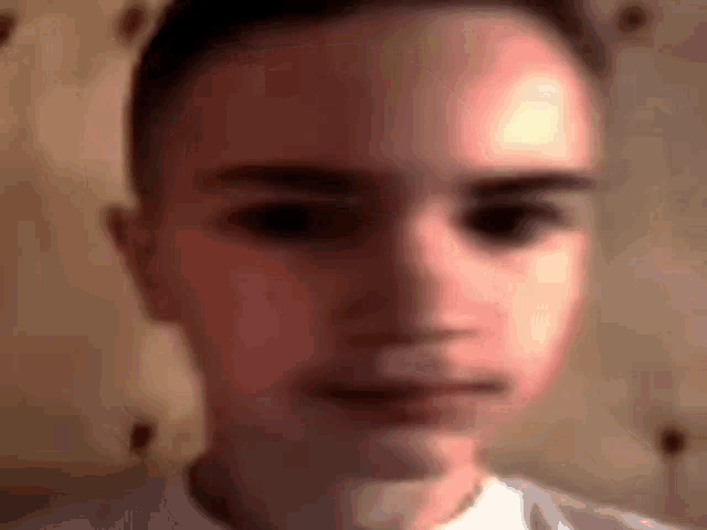 a blurry picture of a young man 's face with a white shirt on .
