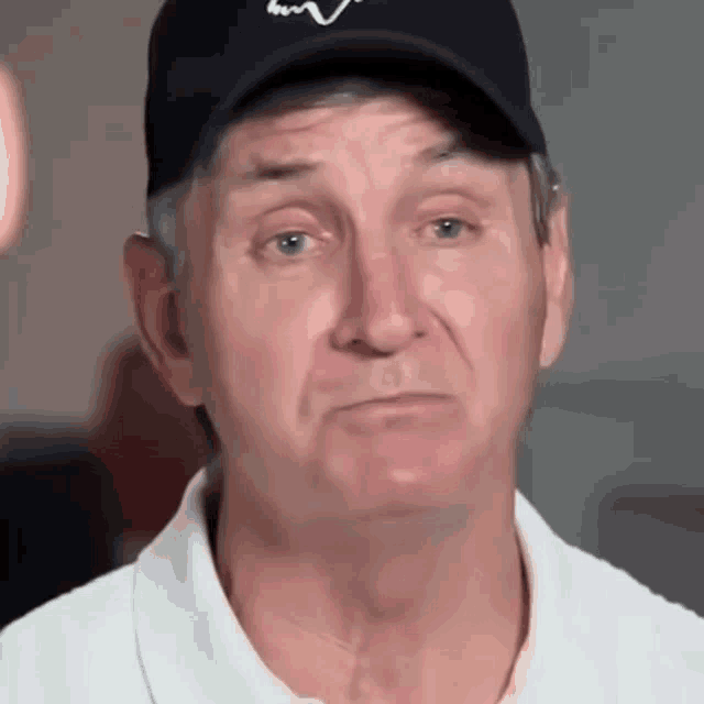 a man wearing a black hat and a white shirt is making a sad face .