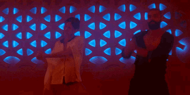 a man and a woman are sitting in front of a wall that has triangles on it