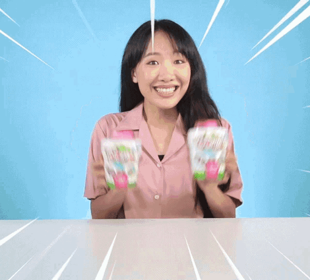 a woman in a pink shirt is holding two bottles of blume juice