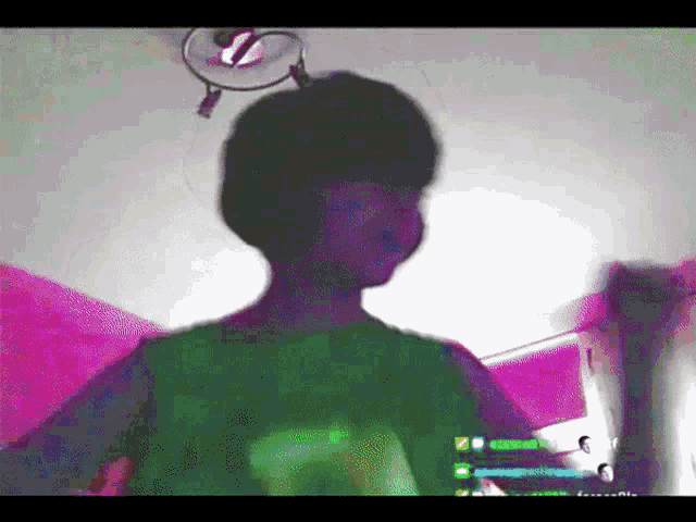 a person in a green shirt is standing in a room with a pink wall