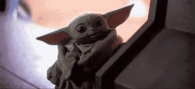 a baby yoda from star wars is sitting on a staircase .