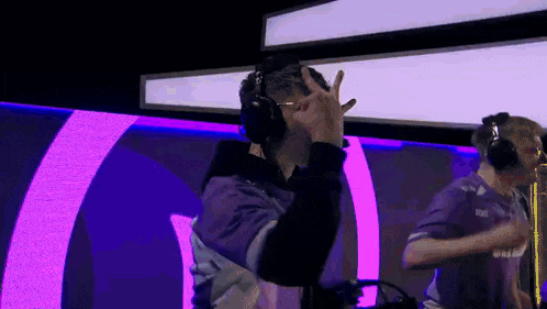a man wearing headphones is standing in front of a purple and pink light .
