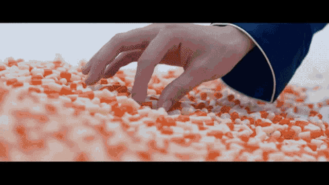 a person 's hand is reaching into a pile of candy