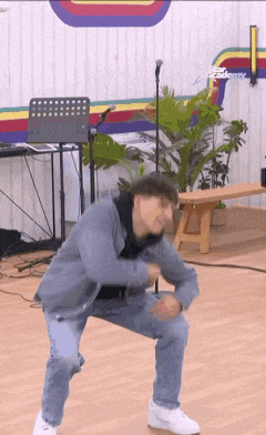 a man is squatting on the floor in front of a microphone in a room .