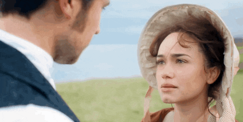 a man and a woman are looking at each other . the woman is wearing a hat .