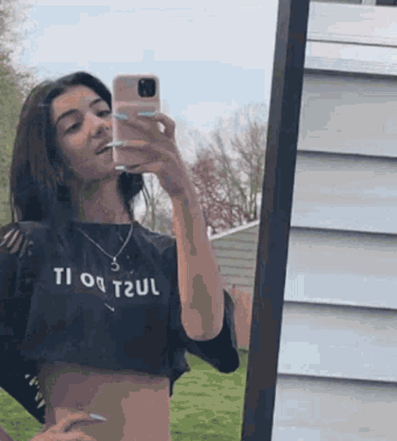 a girl is taking a selfie in front of a mirror .