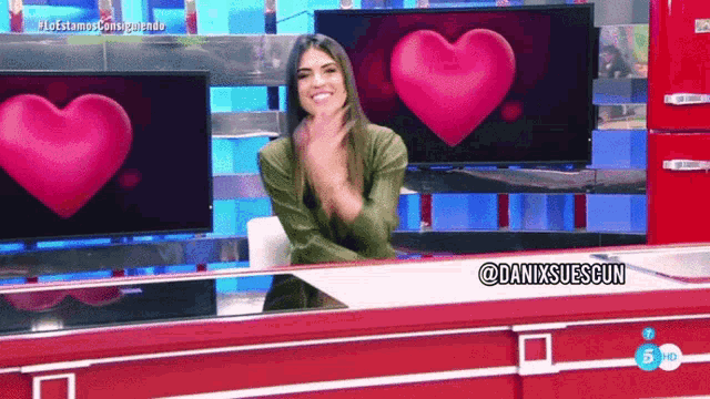 a woman is sitting at a desk in front of a heart shaped tv screen