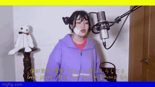 a girl in a purple jacket singing into a microphone with a stuffed animal in the background