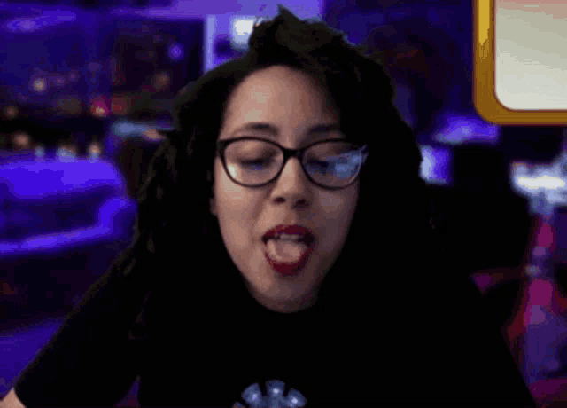 a woman wearing glasses and red lipstick is sticking her tongue out .