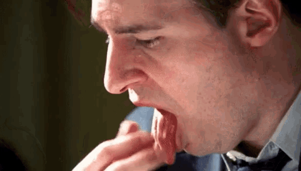 a man in a suit and tie is licking his hand .
