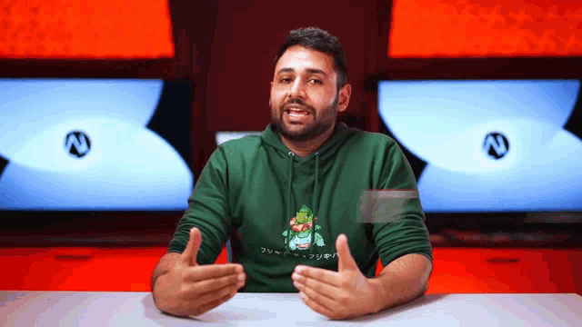 a man wearing a green hoodie with a frog on it is talking