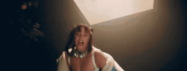 a woman wearing a choker and a white jacket is screaming in a dark room