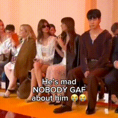 a group of people are sitting in a room and a man is sitting on a yellow carpet .