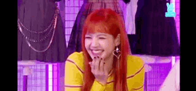 a woman with red hair and a yellow shirt is laughing .