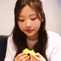 a woman in a white shirt is eating a piece of food .