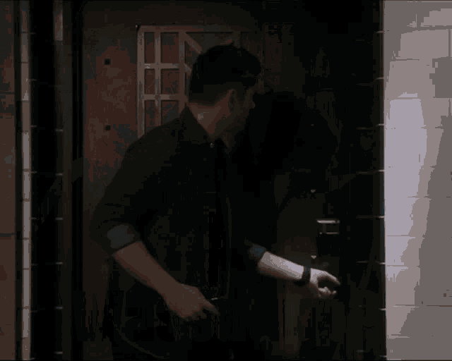 a man in a denim shirt is opening a door