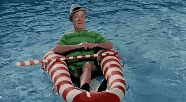a man in a green shirt is sitting in a red and white striped life preserver