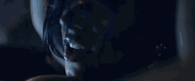 a close up of a woman 's face in the dark with a red light behind her