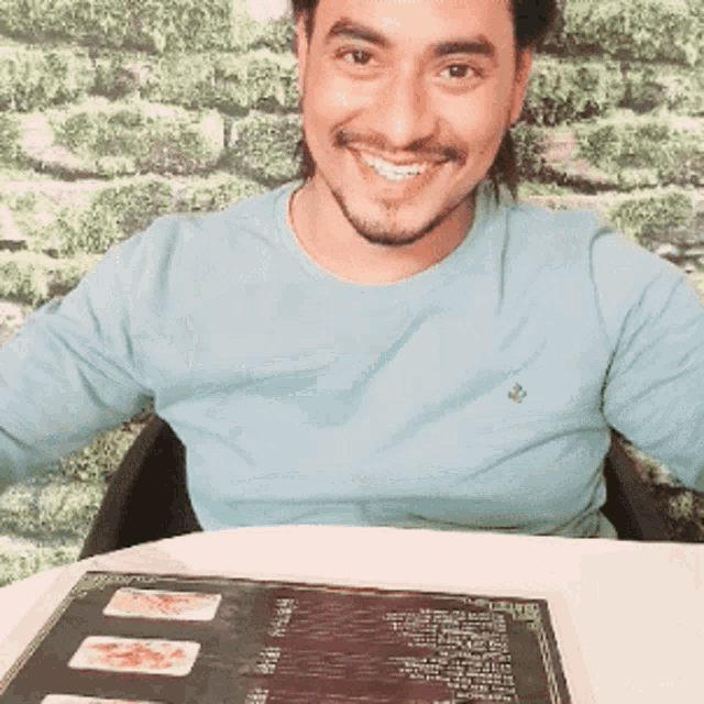 a man in a blue shirt is sitting at a table with a menu on it