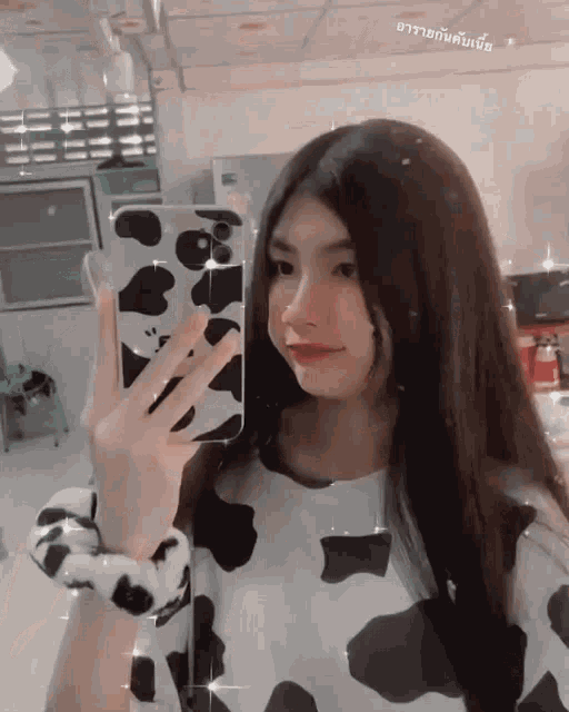 a girl in a cow print shirt is taking a picture of herself with her phone