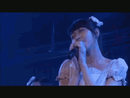 a woman is singing into a microphone on a stage .