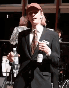 a man in a suit holds a bottle of schweppes wine