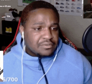 a man wearing ear buds is sitting in front of a microphone with the number 5/700 on the bottom right