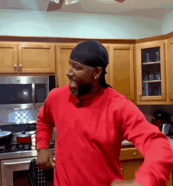a man in a red shirt is standing in a kitchen
