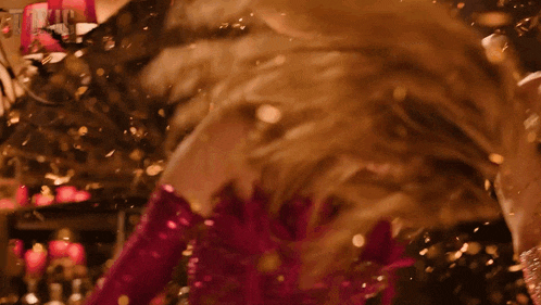 a woman in a pink dress and gloves is surrounded by confetti .