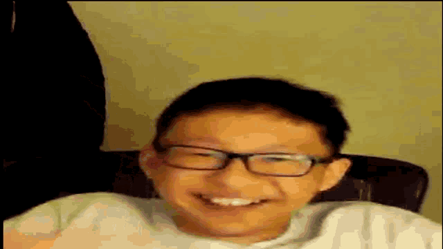 a young boy wearing glasses is smiling and making a funny face .