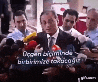a man in a suit and tie is giving a speech in front of a group of reporters .