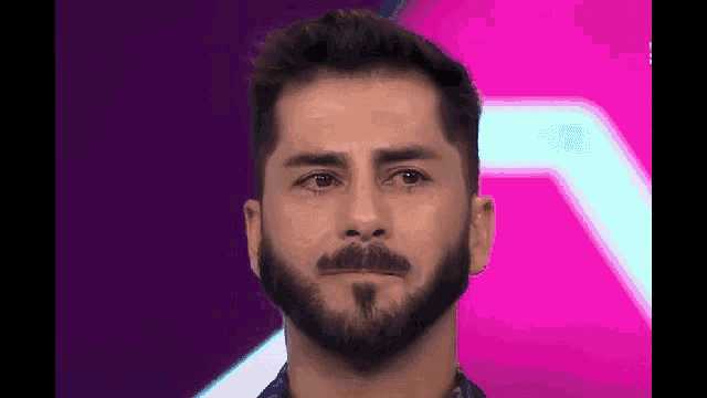 a man with a beard and mustache is crying on a pink background .