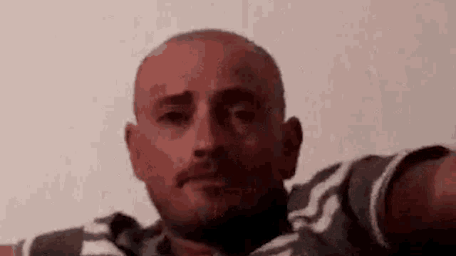 a man with a beard is taking a selfie with his arm outstretched .